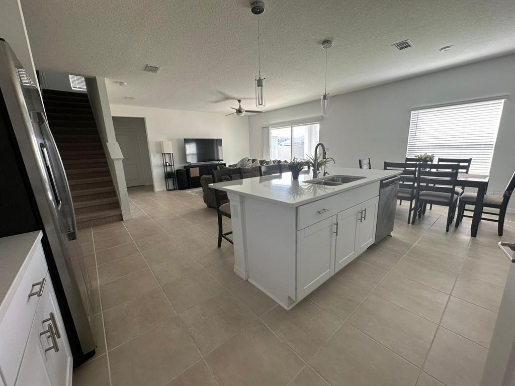 A kitchen with a white island and stainless steel appliances overlooks an open living area — 5656 COSTA BLANCA WAY, DAVENPORT, FL