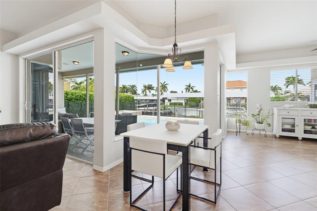 A dining area with a white table and chairs overlooks a pool and canal — 5020 SW 8TH PLACE, CAPE CORAL, FL
