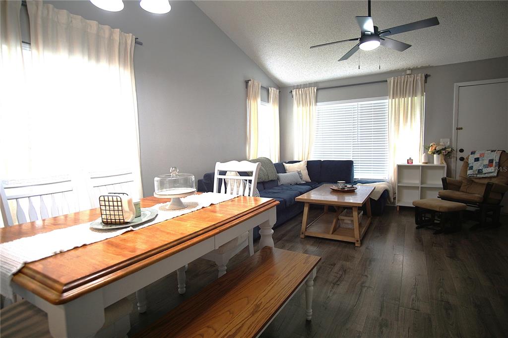 A dining area with a wooden table and bench opens into a living room — 7807 AMBERLEA COURT UNIT 7807, TAMPA, FL