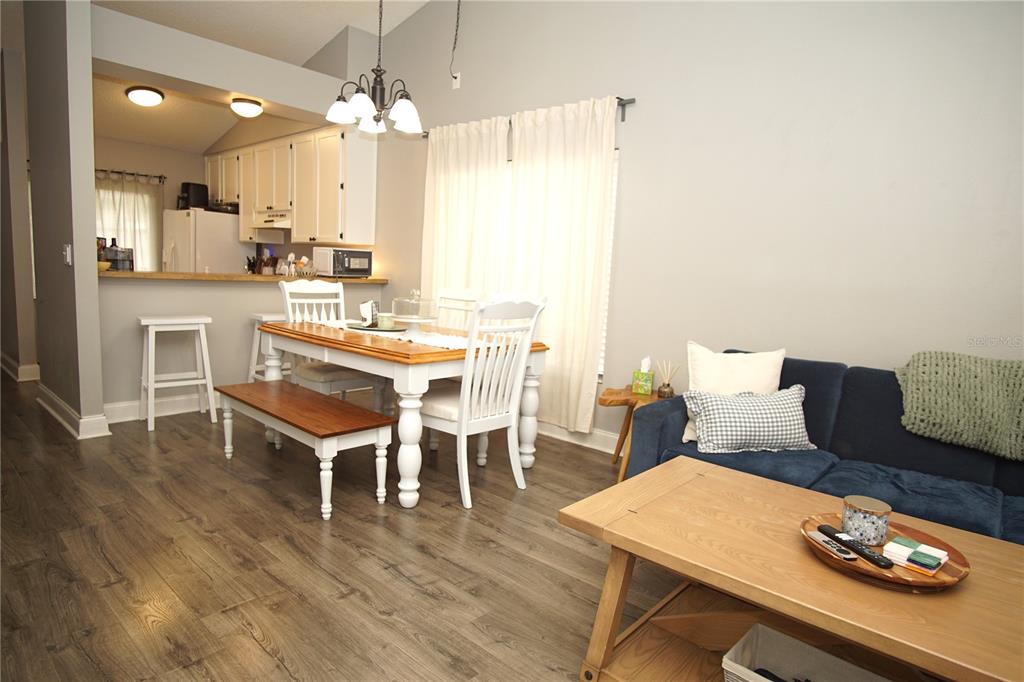 A dining area with a wooden table and bench sits adjacent to a living room — 7807 AMBERLEA COURT UNIT 7807, TAMPA, FL