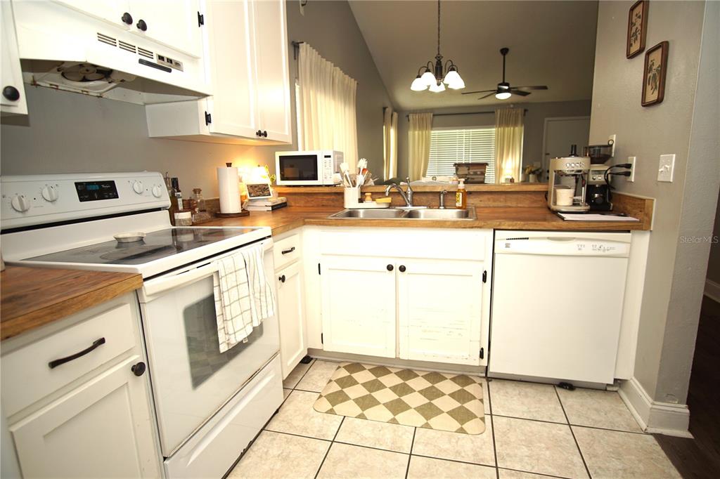 A kitchen features white cabinets, a white stove, a dishwasher, and wood-look countertops — 7807 AMBERLEA COURT UNIT 7807, TAMPA, FL