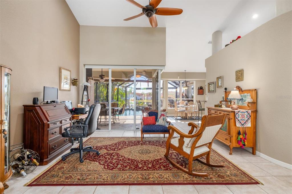A living room with a desk, rocking chair, area rug, and sliding doors to a pool — 590 TOULOUSE DRIVE, PUNTA GORDA, FL