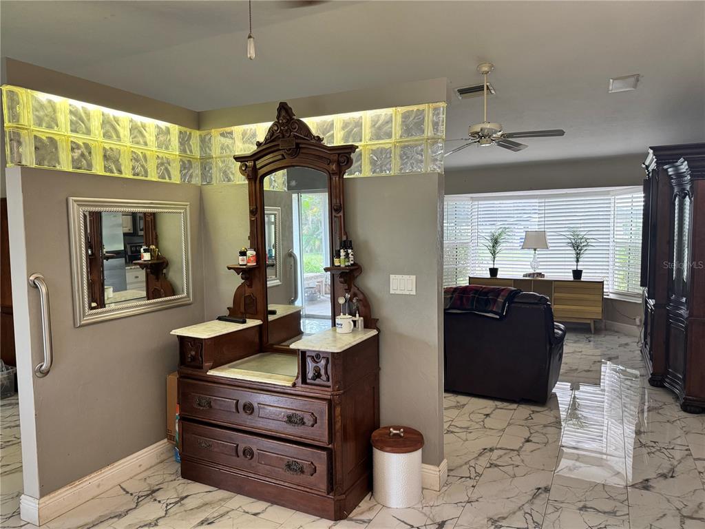 A room features a vintage wooden vanity, glass block wall accents, and marble-patterned tile flooring — 30048 OAK ROAD, PUNTA GORDA, FL