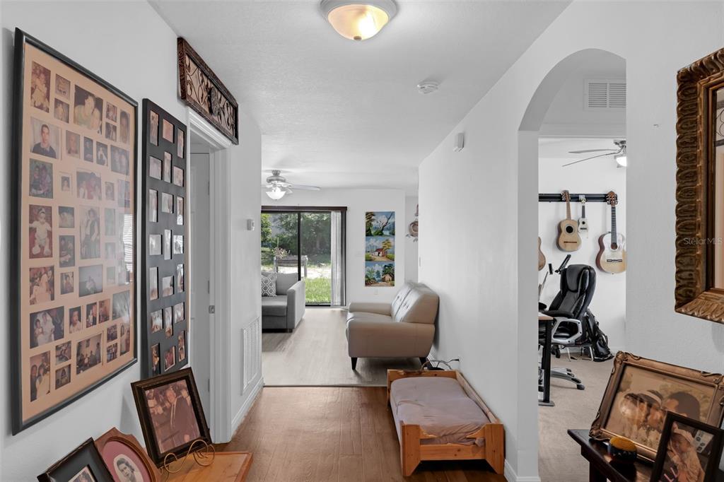 A hallway with wood-look flooring leads to a living area with a sliding glass door — 340 PHEASANT DRIVE, HAINES CITY, FL