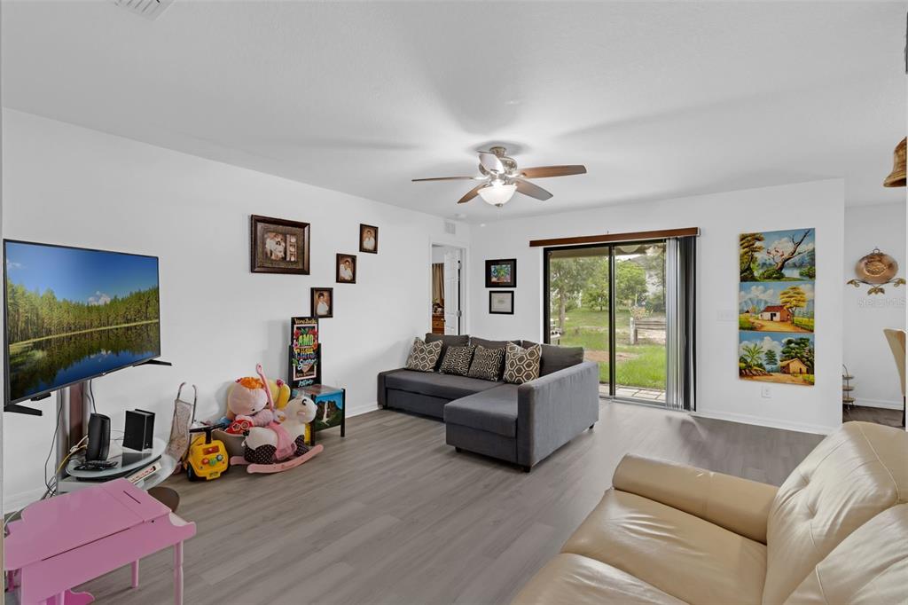 A living room with gray wood-look flooring, a gray sectional sofa, and a television — 340 PHEASANT DRIVE, HAINES CITY, FL
