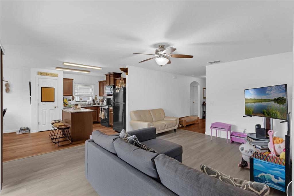 An open-concept living room with gray flooring flows into a kitchen with dark wood cabinets — 340 PHEASANT DRIVE, HAINES CITY, FL