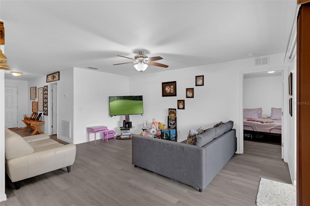 A living room with gray flooring, a gray sofa, a television, and a ceiling fan — 340 PHEASANT DRIVE, HAINES CITY, FL