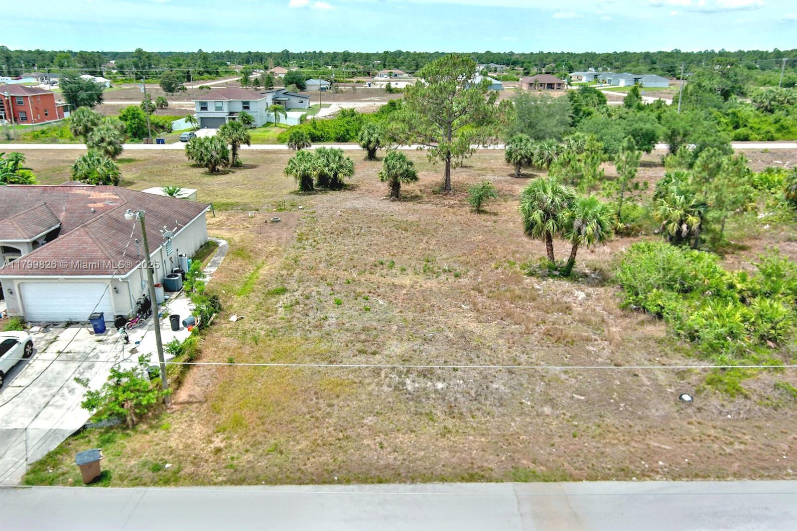 An aerial view shows a vacant, grassy lot situated next to a residential home — 914 S Mercury Ave, Lehigh Acres FL 33974, LEHIGH ACRES, FL