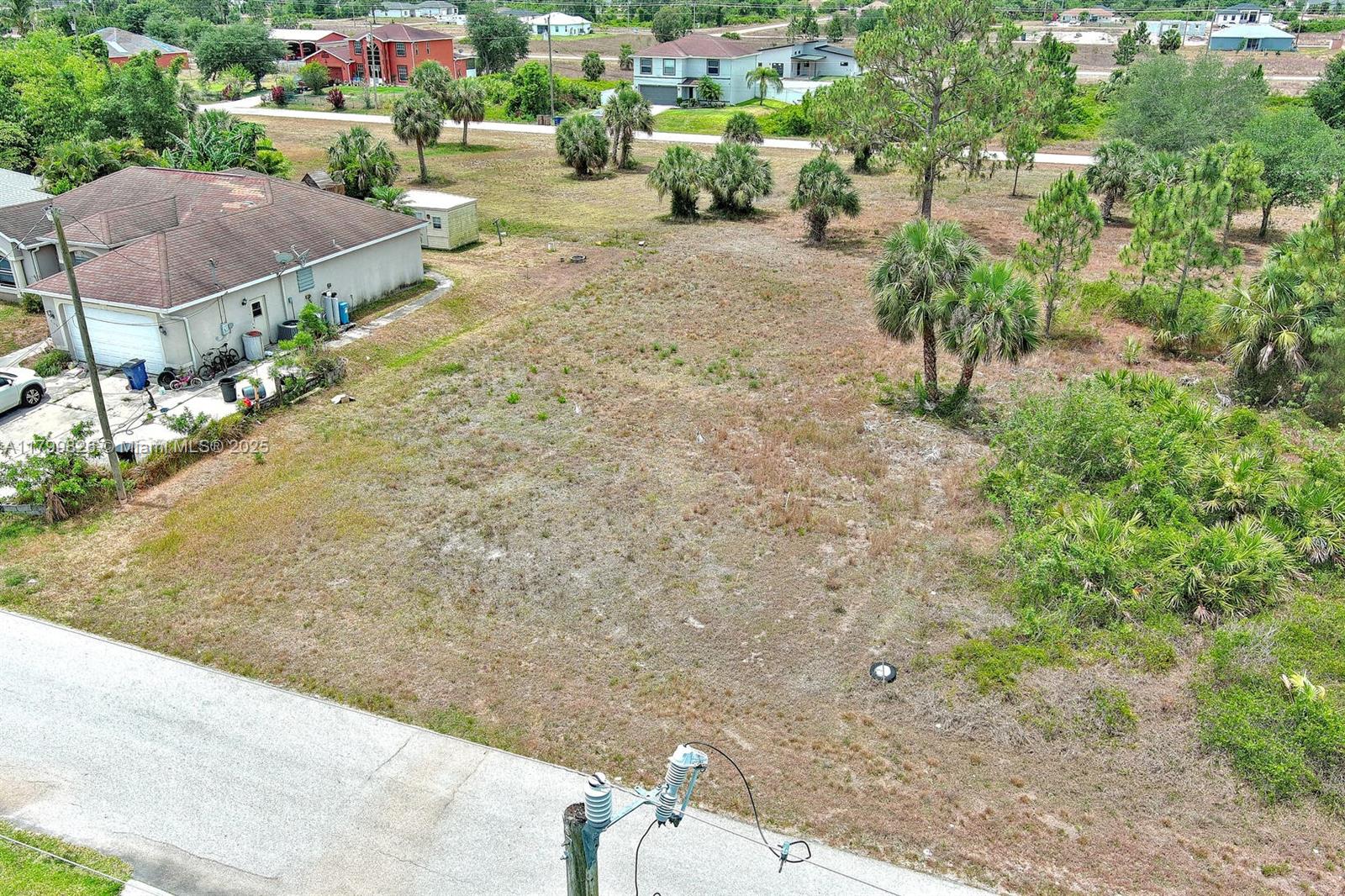 An aerial view shows a vacant residential lot next to a house with a driveway — 914 S Mercury Ave, Lehigh Acres FL 33974, LEHIGH ACRES, FL