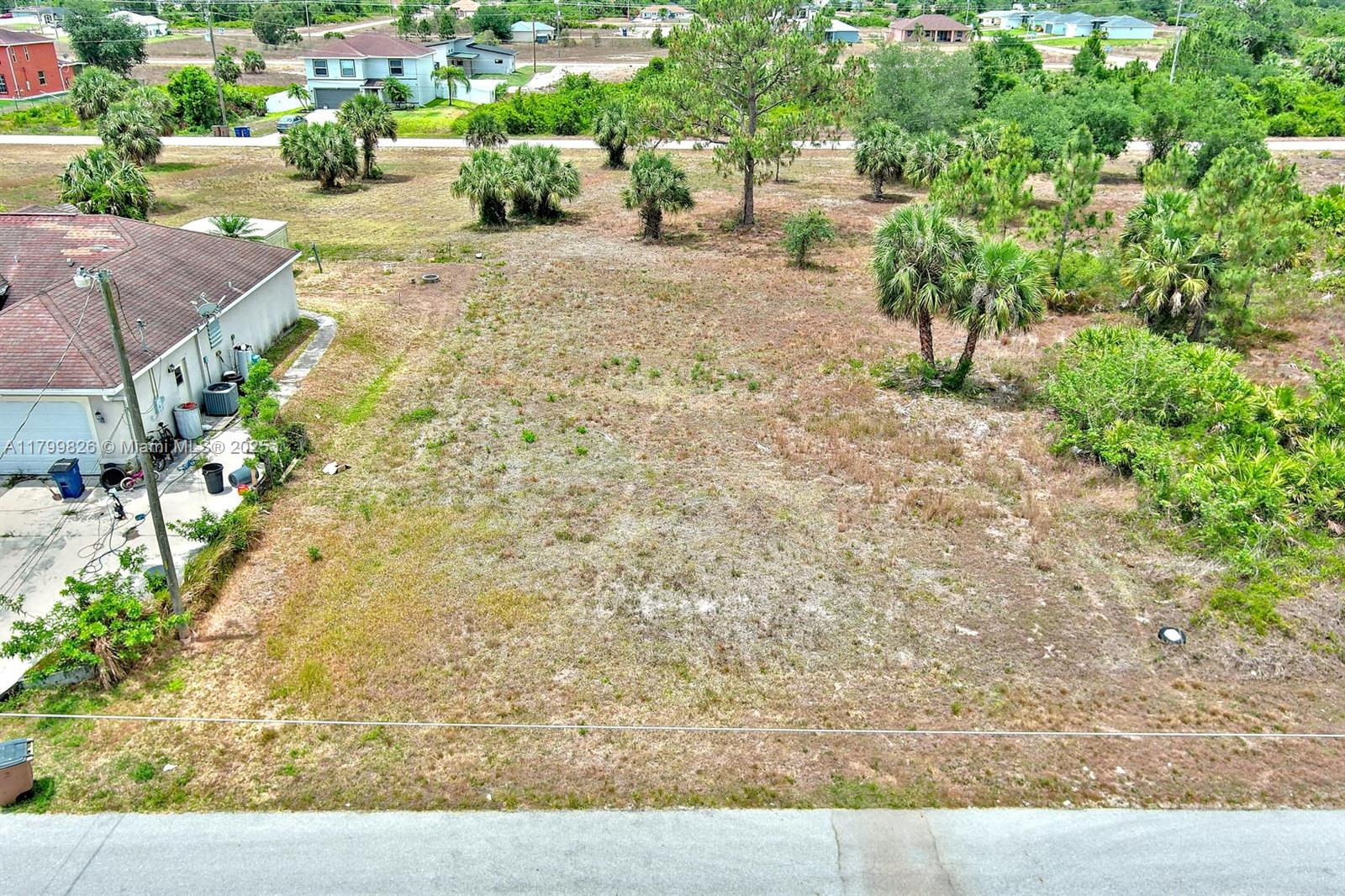 An aerial view shows a vacant, grassy residential lot adjacent to a house with a driveway — 914 S Mercury Ave, Lehigh Acres FL 33974, LEHIGH ACRES, FL