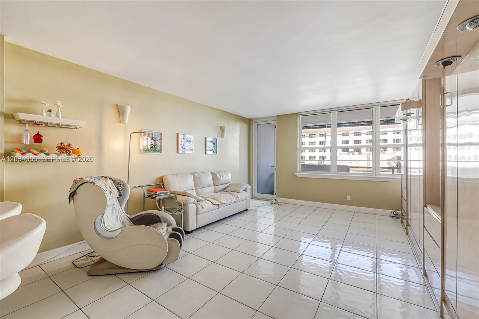 A living room features white tile flooring, a beige sofa, a massage chair, and large windows — 100 Lincoln Rd # 502, Miami Beach FL 33139, MIAMI BEACH, FL