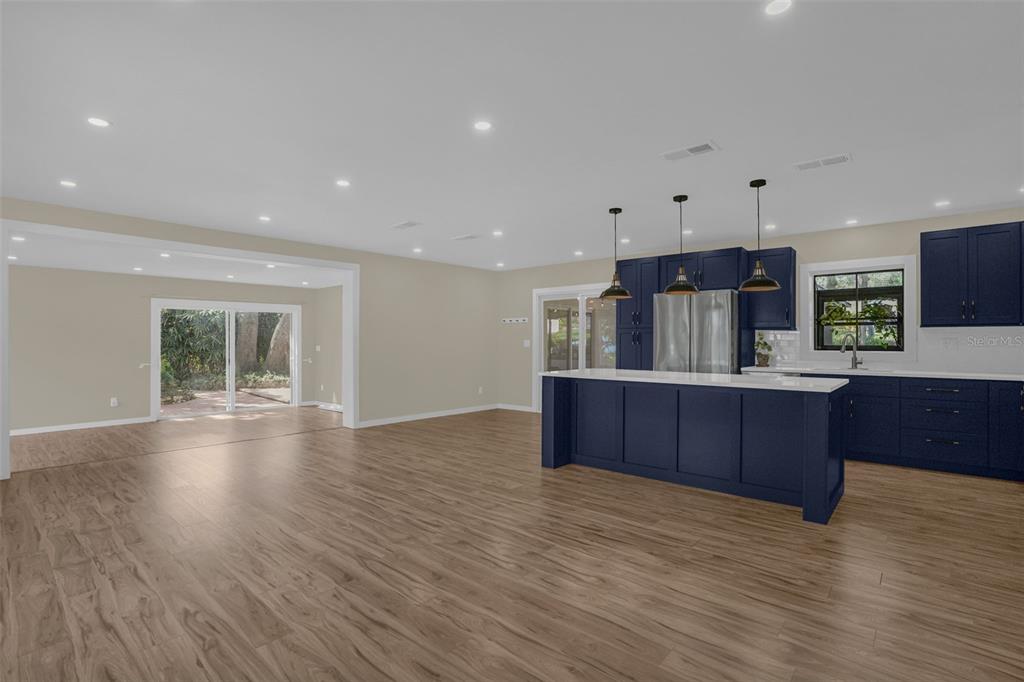 A kitchen with dark blue cabinets and a white island sits in an open-concept room — 10945 BIG TREE LANE, CLERMONT, FL