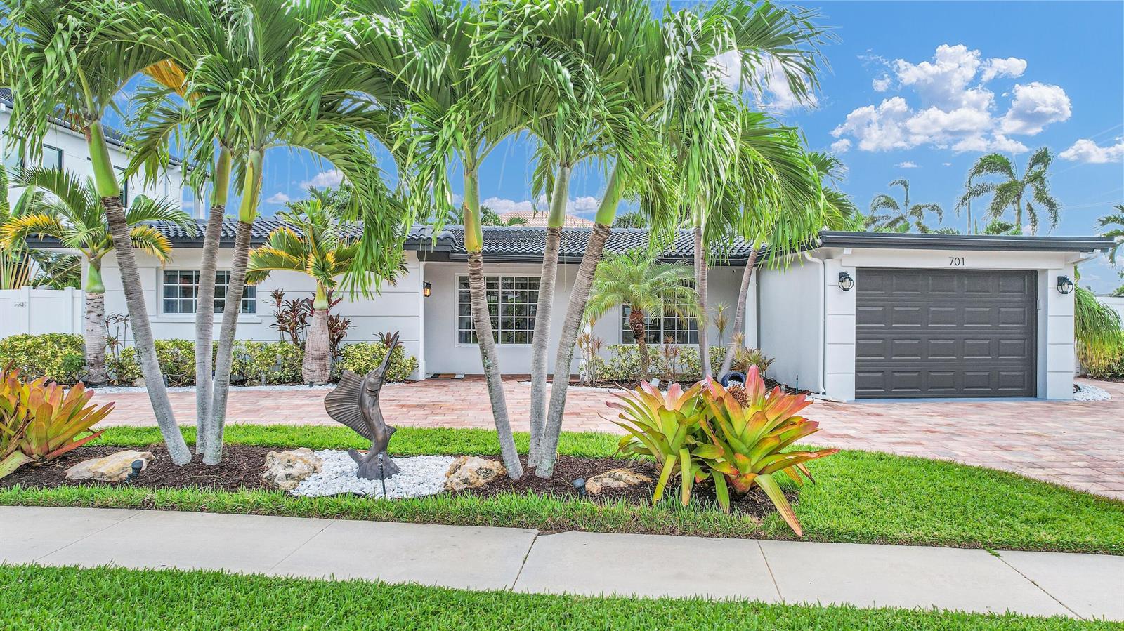 A single-story house with a dark garage door, palm trees, and a brick driveway — 701 Appleby Street, Boca Raton FL 33487, BOCA RATON, FL