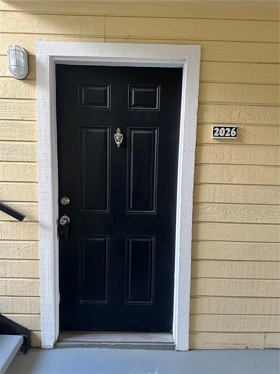 A black front door with a silver knocker is set in a yellow-sided exterior wall — 1055 S HIAWASSEE ROAD UNIT 2026, ORLANDO, FL