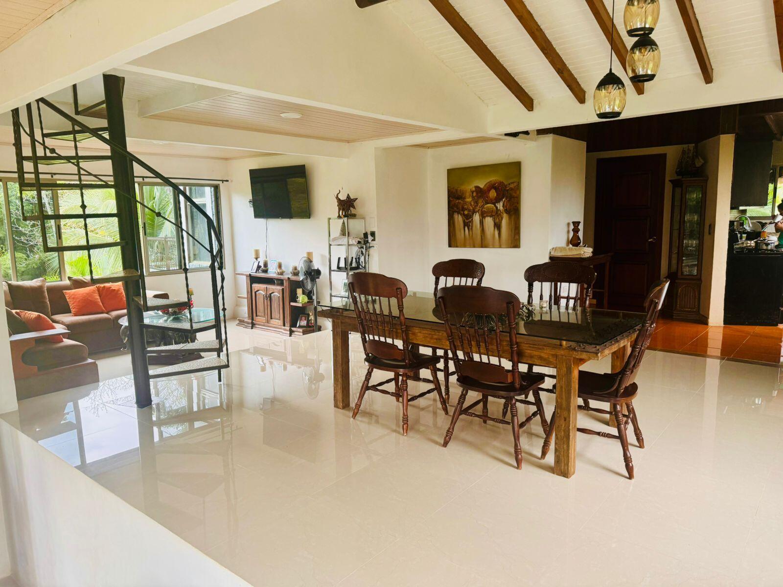 A dining area with a wooden table and chairs sits beside a black spiral staircase — 141 N El Tanque Fortuna San Carlos Street, FL