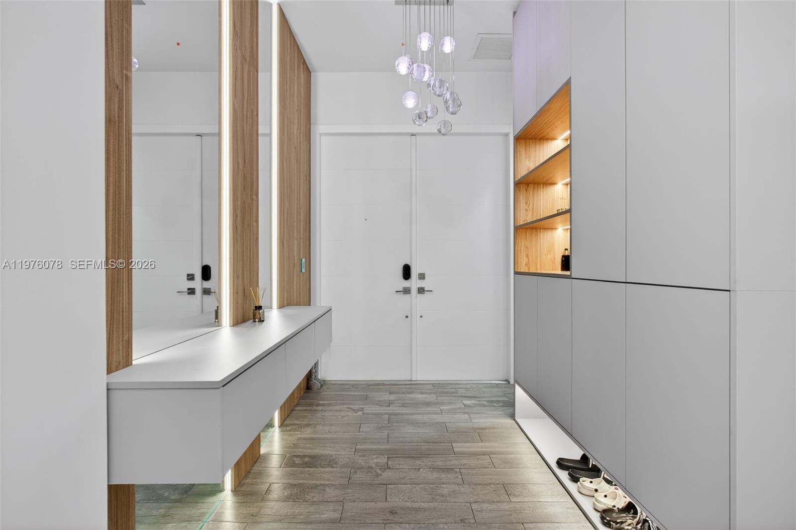 A modern entryway features a floating white console, wood paneling, and built-in storage cabinets — 11174 NW 72nd Pl, Parkland FL 33076, PARKLAND, FL