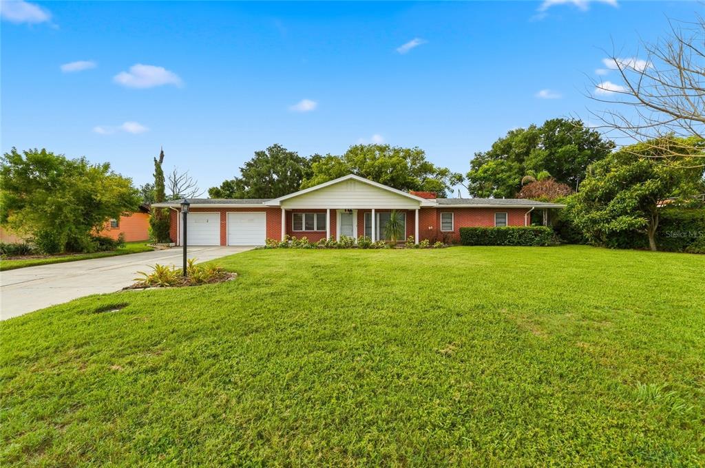 A single-story brick house with a two-car garage and a large front lawn — 1475 S LAKE HOWARD DRIVE, WINTER HAVEN, FL