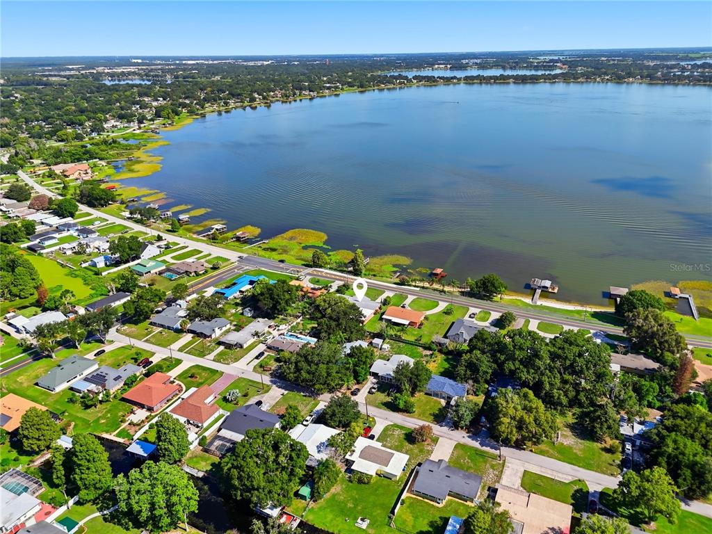 An aerial view shows a residential neighborhood situated along the shore of a large lake — 1475 S LAKE HOWARD DRIVE, WINTER HAVEN, FL
