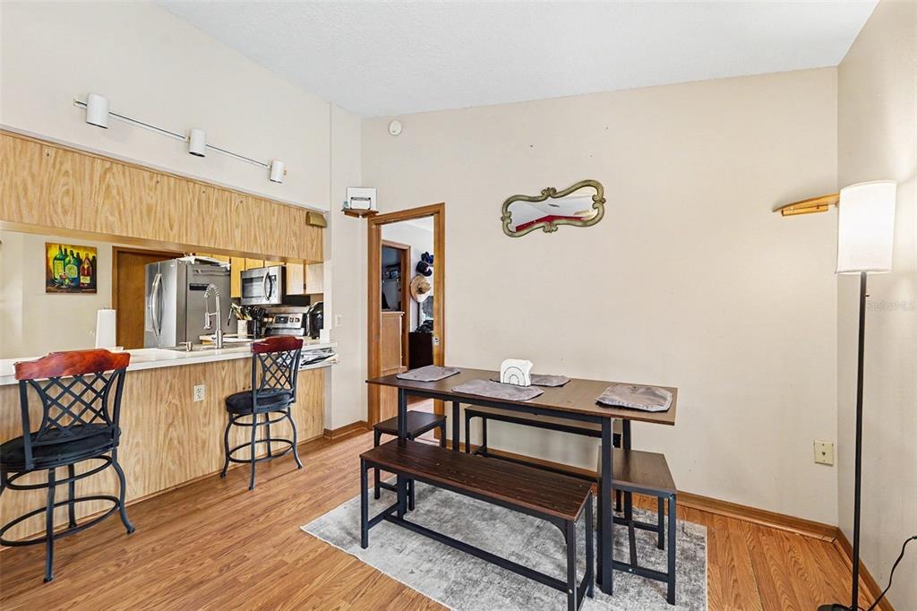 A dining area with a wooden table, benches, and a breakfast bar with two stools — 11363 NORVELL ROAD, SPRING HILL, FL