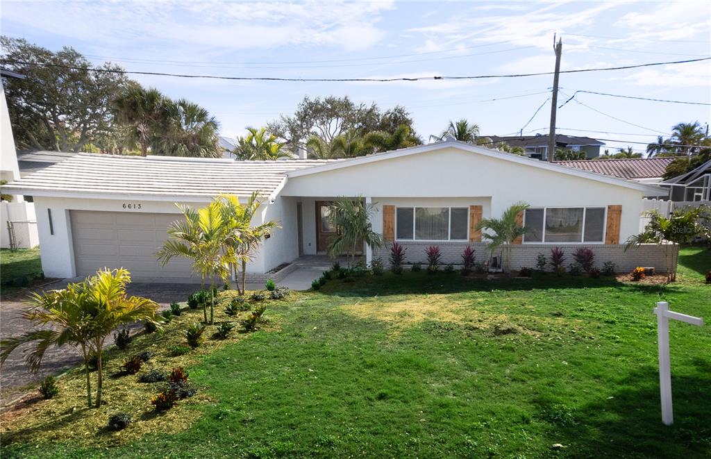 A single-story house with a white exterior, a two-car garage, and a landscaped front yard — 6613 BLUE HERON DRIVE S, ST PETERSBURG, FL