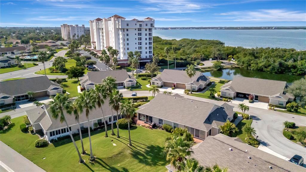 An aerial view shows residential villas, a tall apartment building, and a nearby body of water — 2905 CAPTAINS COURT UNIT 0, PALMETTO, FL