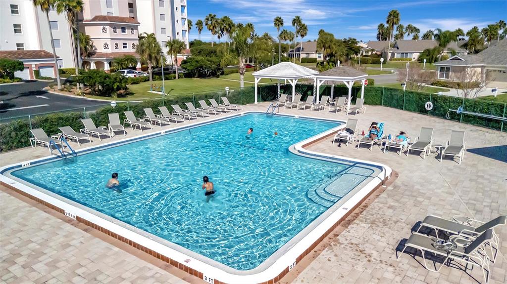 An outdoor swimming pool with lounge chairs and two gazebos sits beside a multi-story building — 2905 CAPTAINS COURT UNIT 0, PALMETTO, FL