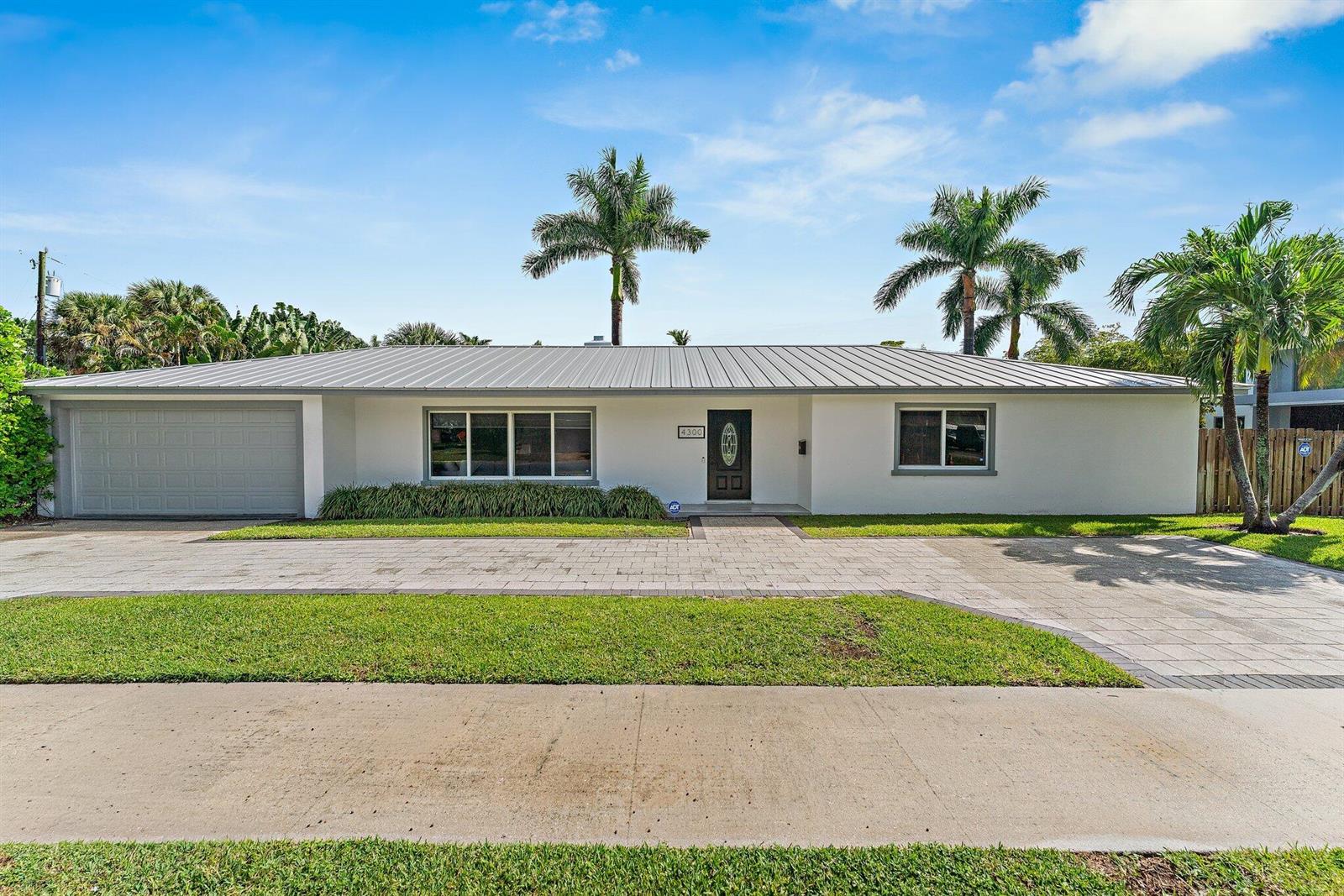 A single-story house with a metal roof, white stucco exterior, and a paved driveway — 4300 Washington Road, West Palm Beach FL 33405, WEST PALM BEACH, FL