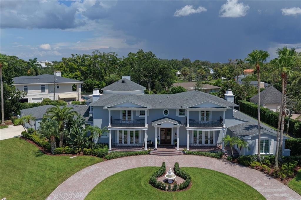 An aerial view of a two-story gray house with a circular driveway and fountain — 155 WILLADEL DRIVE, BELLEAIR, FL