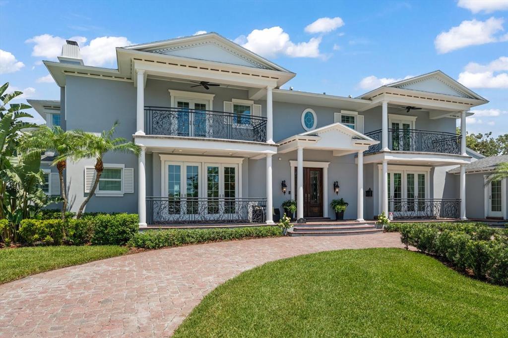 A two-story gray house with a brick driveway, white columns, and wrought-iron balconies — 155 WILLADEL DRIVE, BELLEAIR, FL