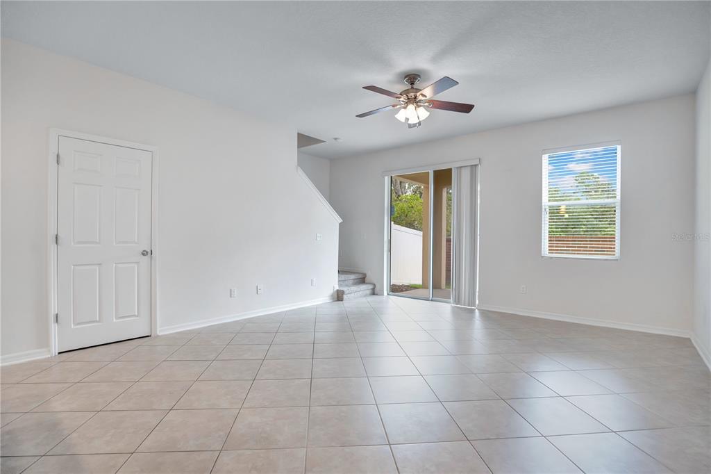 A bright living room features light tile flooring, a ceiling fan, and sliding glass doors — 196 WINDFLOWER WAY, OVIEDO, FL