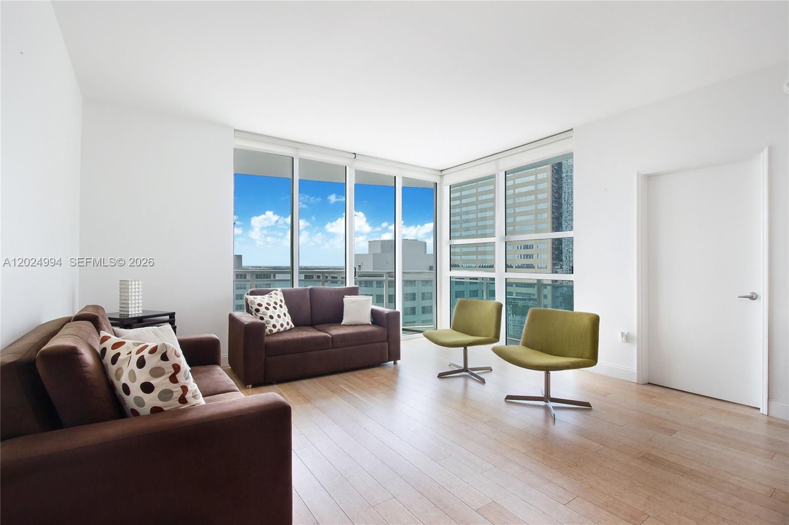 A living room features brown sofas, two green chairs, wood floors, and floor-to-ceiling windows — 950 Brickell Bay Dr # 1911, Miami FL 33131, MIAMI, FL