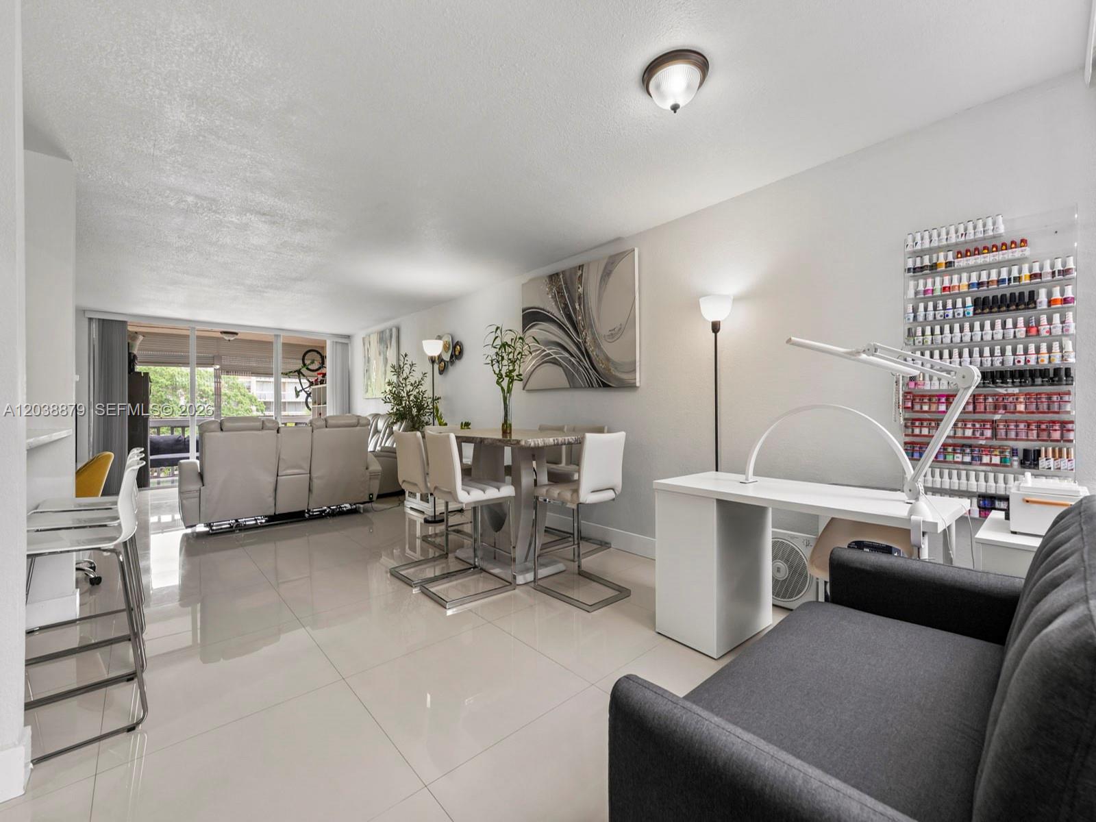 A living and dining area features white tile floors, a nail station, and balcony access — 7021 Environ Blvd # 320, Lauderhill FL 33319, LAUDERHILL, FL