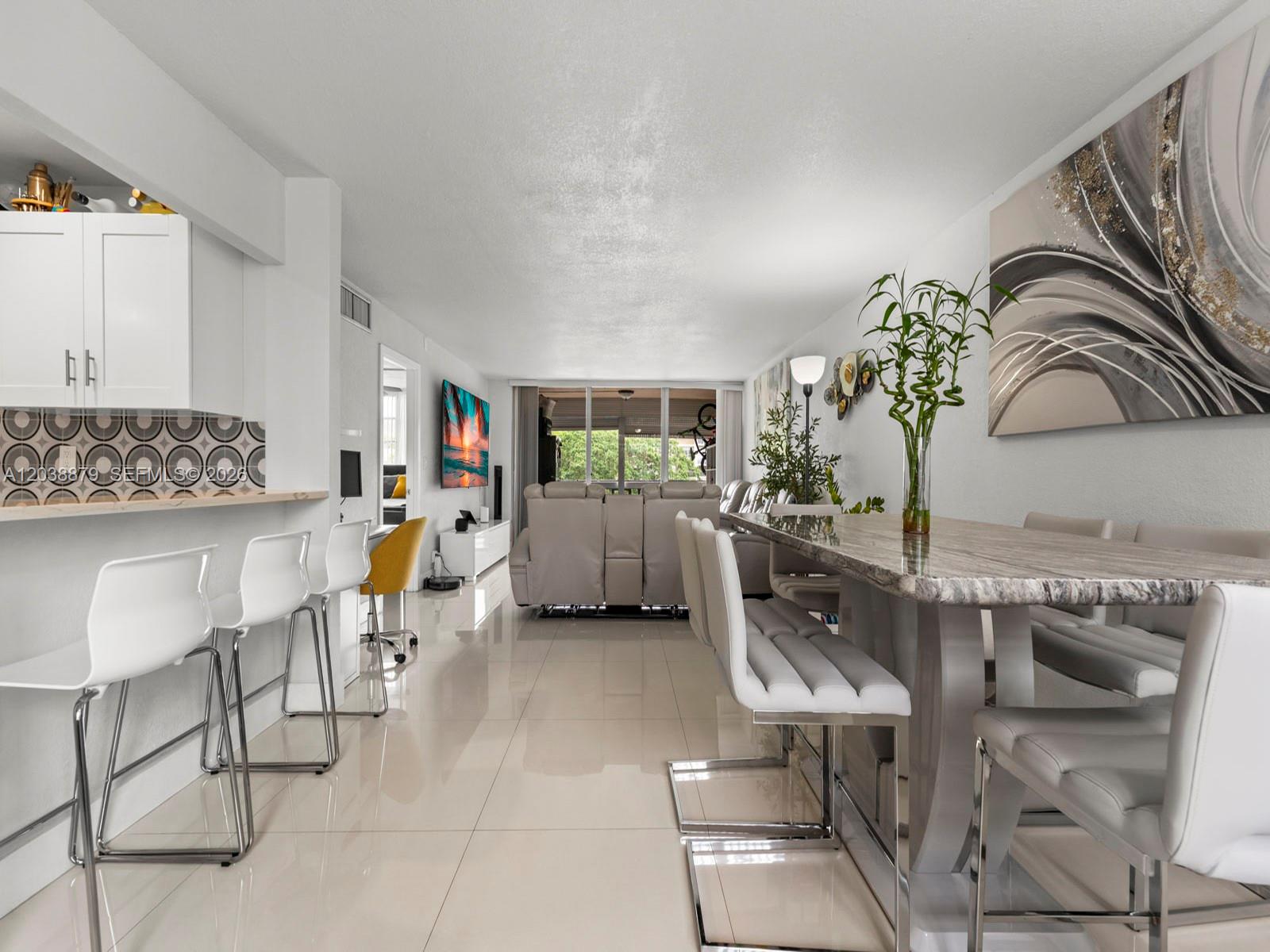 An open-concept living and dining area features white tile floors, a breakfast bar, and furniture — 7021 Environ Blvd # 320, Lauderhill FL 33319, LAUDERHILL, FL
