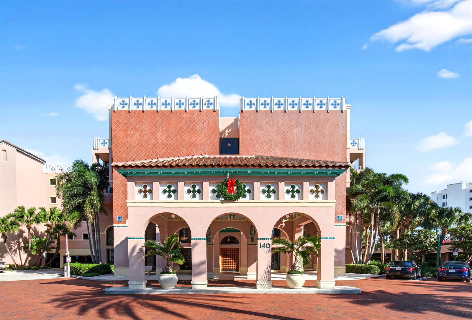 The exterior of a pink building features a covered arched entryway with a holiday wreath — 140 SE 5th Avenue # 448, Boca Raton FL 33432, BOCA RATON, FL