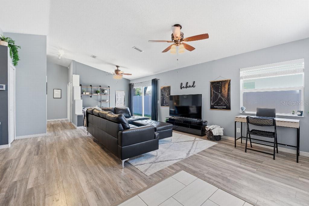 A living room with light gray walls, wood-look flooring, a black sectional, and a desk — 25130 ENSLEY ROAD, SORRENTO, FL