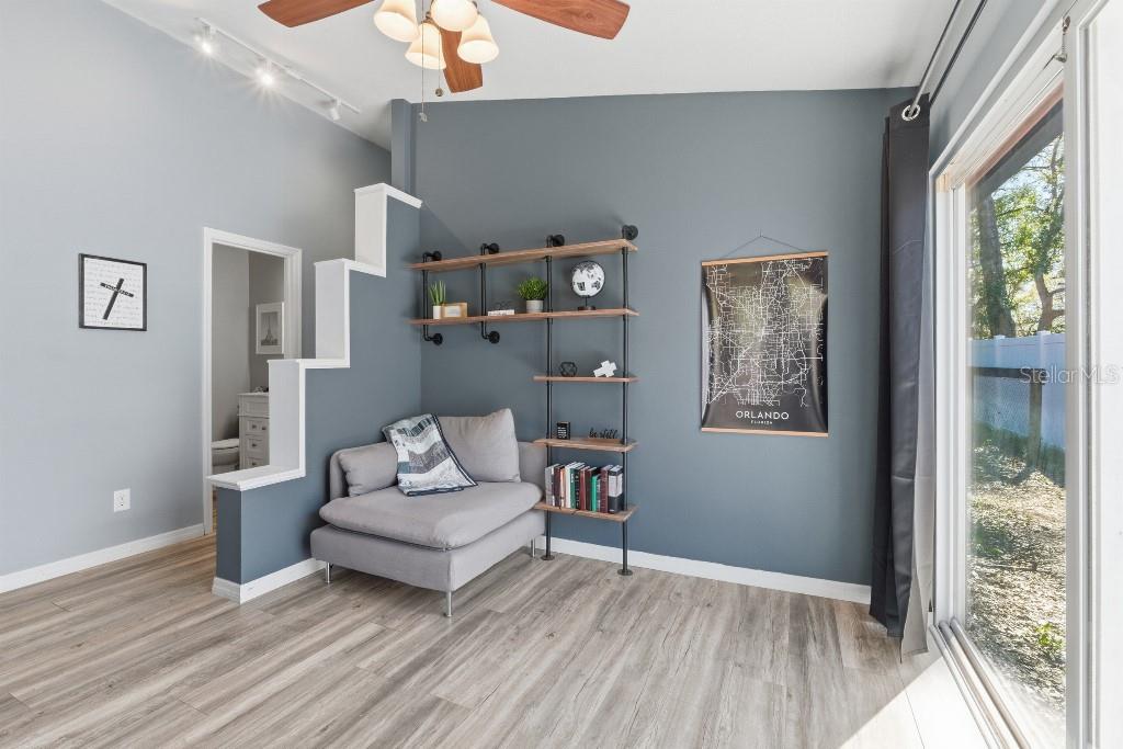 A living room features gray walls, wood-look flooring, a corner chair, and industrial-style shelving — 25130 ENSLEY ROAD, SORRENTO, FL