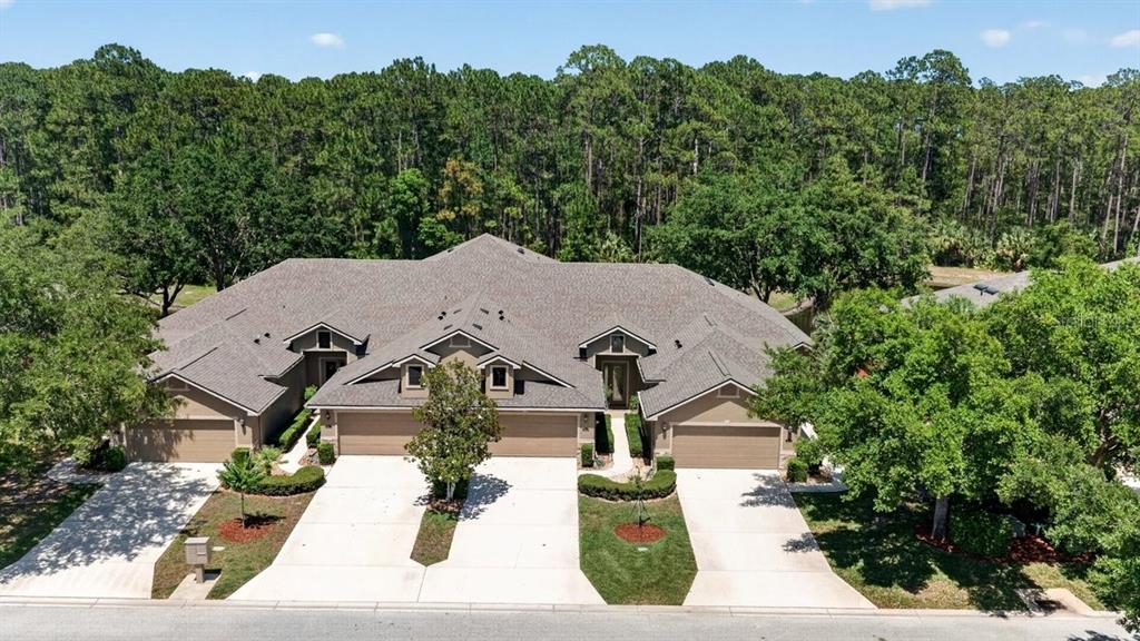 An aerial view of a tan, three-unit townhouse building with gray roofs and concrete driveways — 1109 HANSBERRY COURT, ORMOND BEACH, FL