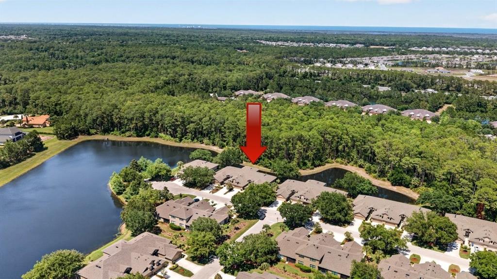 An aerial view shows a residential complex with multiple buildings situated near a lake — 1109 HANSBERRY COURT, ORMOND BEACH, FL