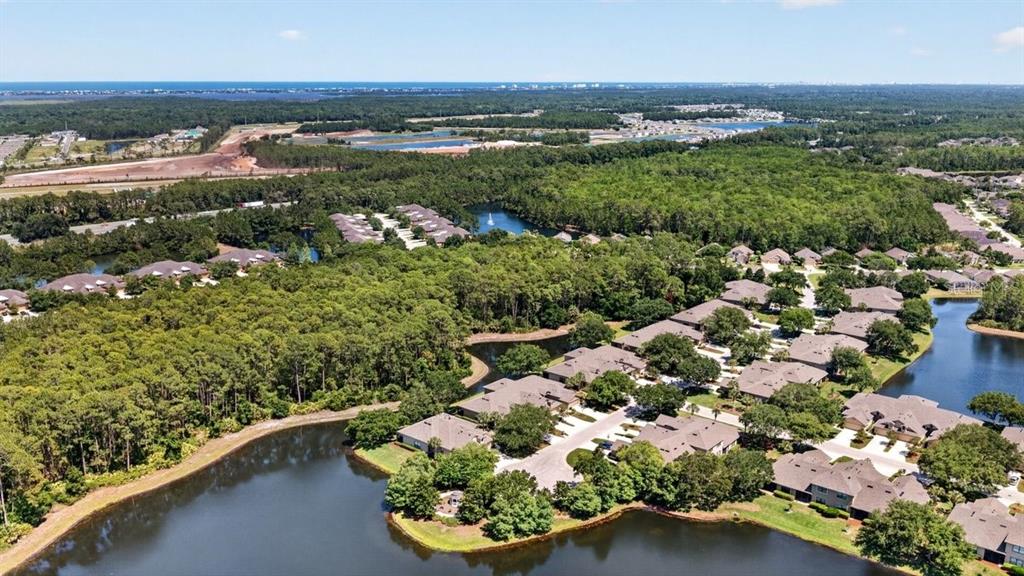 An aerial view shows a residential neighborhood with multiple buildings surrounded by trees and ponds — 1109 HANSBERRY COURT, ORMOND BEACH, FL