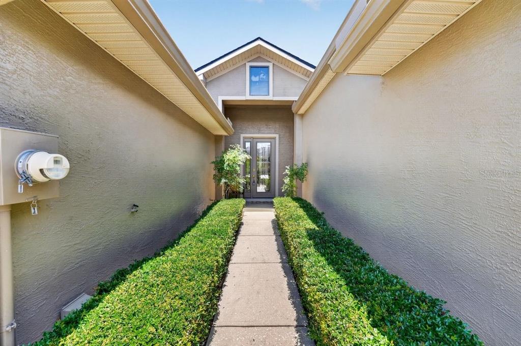 A concrete walkway leads between two hedges to the front entrance of a house — 1109 HANSBERRY COURT, ORMOND BEACH, FL