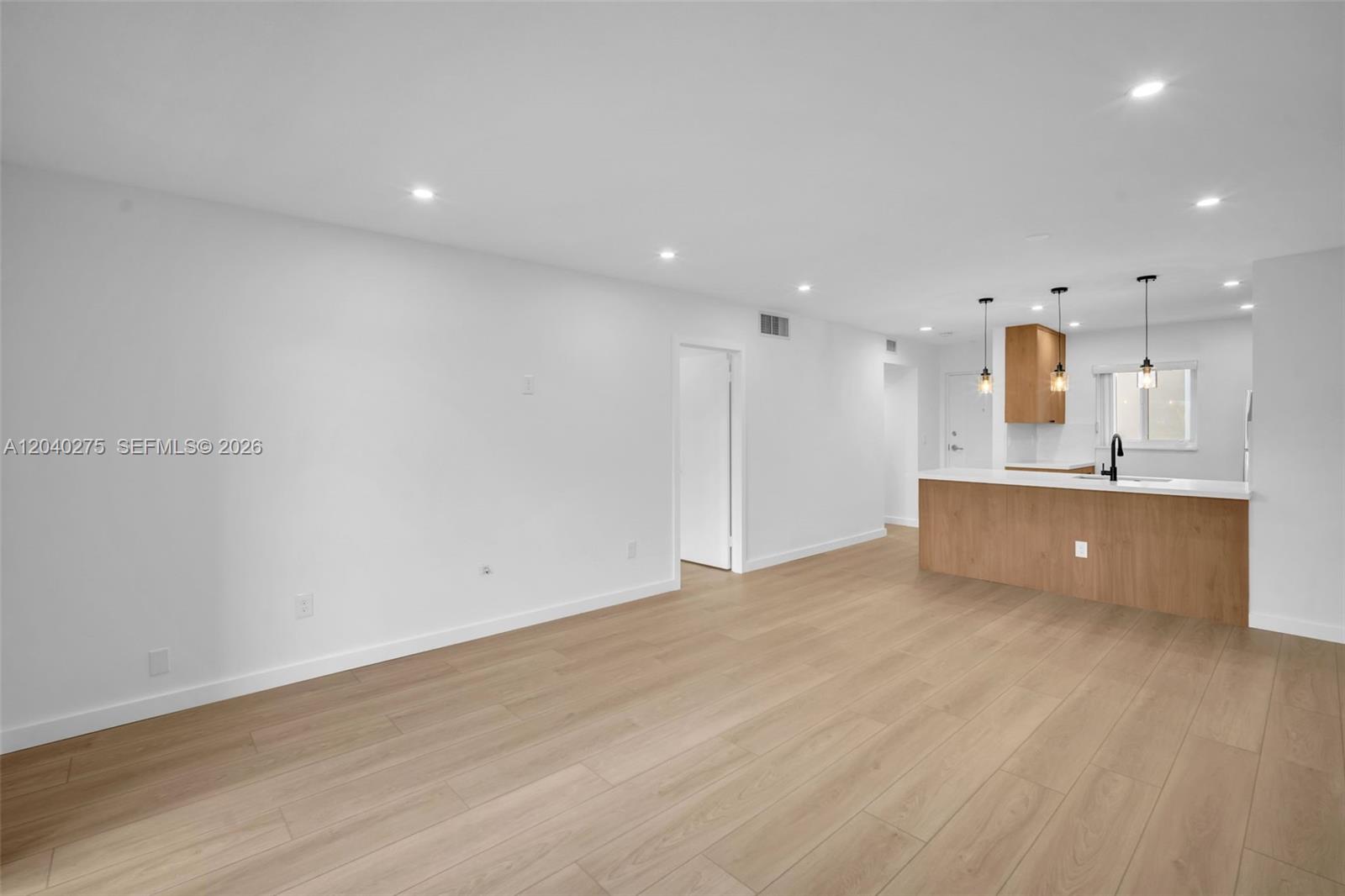 A bright, open-concept living area features light wood flooring and a modern kitchen island — 8101 Camino Real # c402, Miami FL 33143, MIAMI, FL