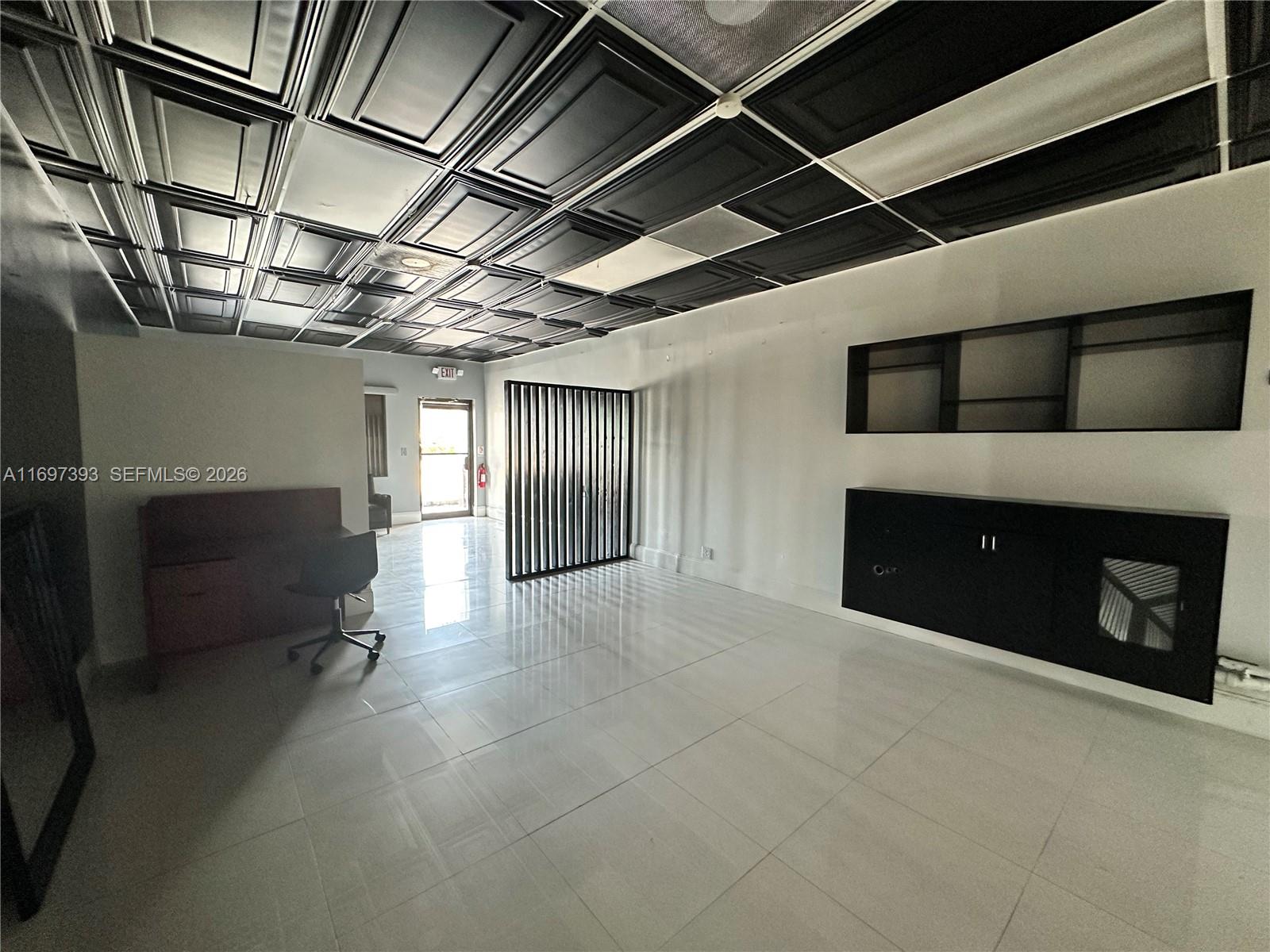 An office space features a black coffered ceiling, white tile floors, and built-in wall shelving — 2922 N State Road 7, Margate FL 33063, MARGATE, FL