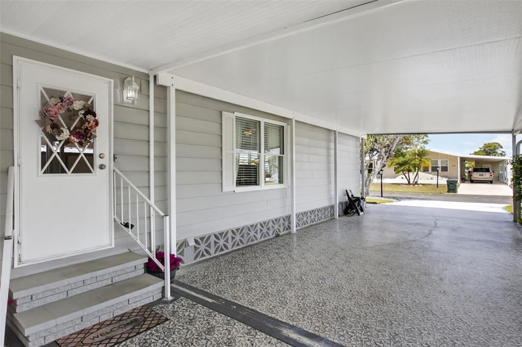 A gray mobile home exterior features a covered carport, a front door with a wreath, and steps — 487 LOMA LINDA, NORTH PORT, FL