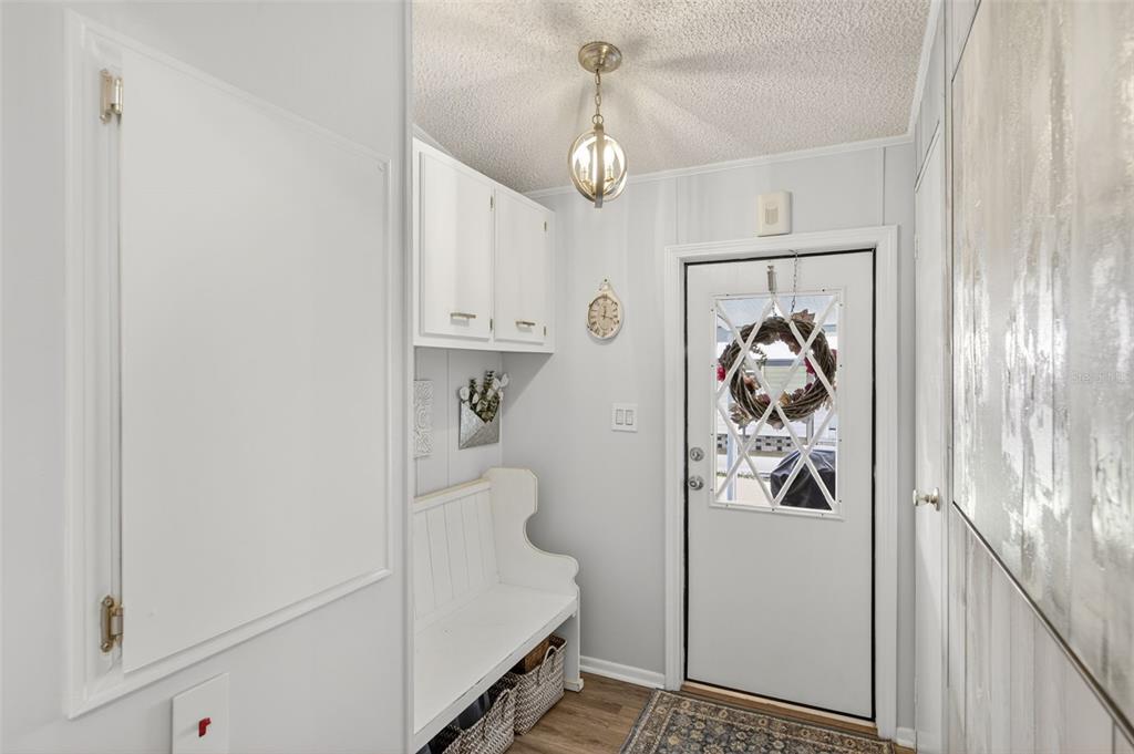 A bright entryway features a white bench, overhead cabinets, a light fixture, and a door — 487 LOMA LINDA, NORTH PORT, FL