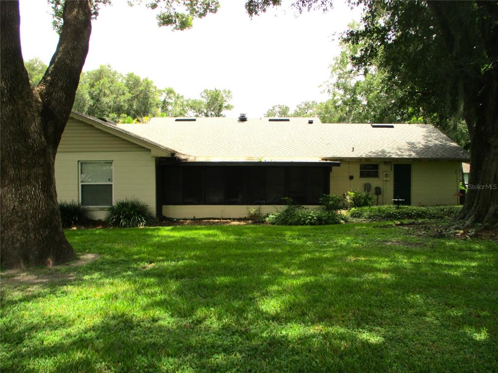 The exterior of a single-story house features a screened-in porch and large shade trees — 1118 KNIGHTS PLACE, LAKELAND, FL