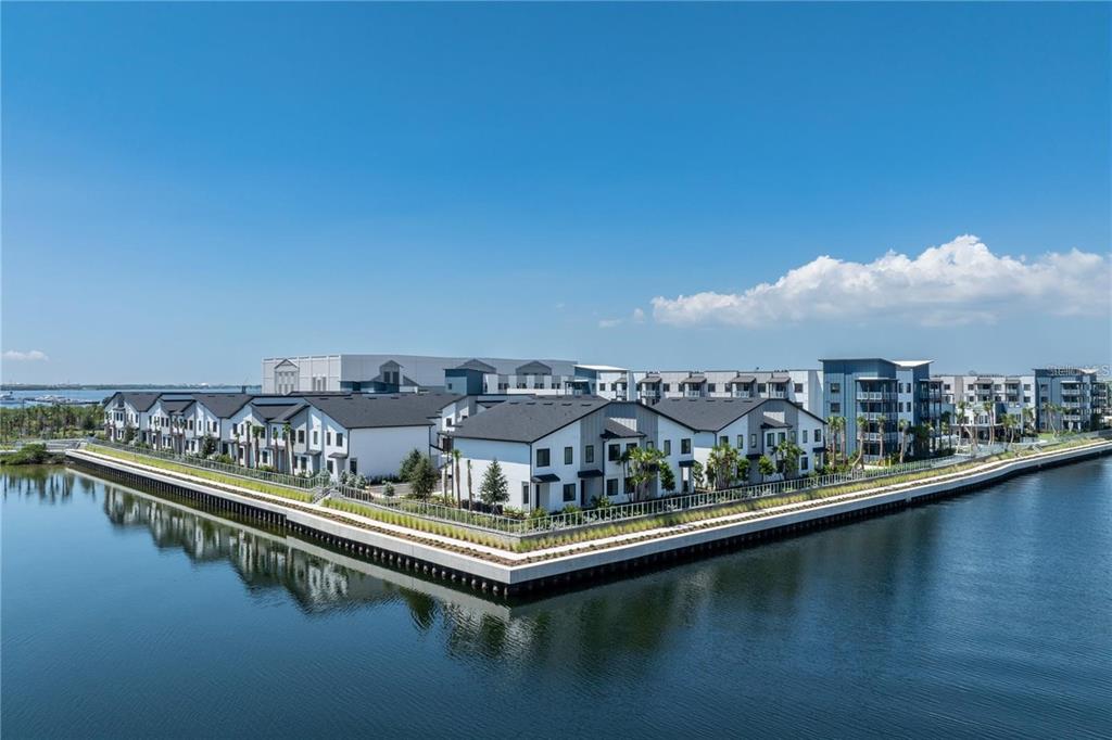 An aerial view of a modern apartment complex situated along a waterfront with calm reflections — 5127 W TYSON AVENUE UNIT TH1, TAMPA, FL