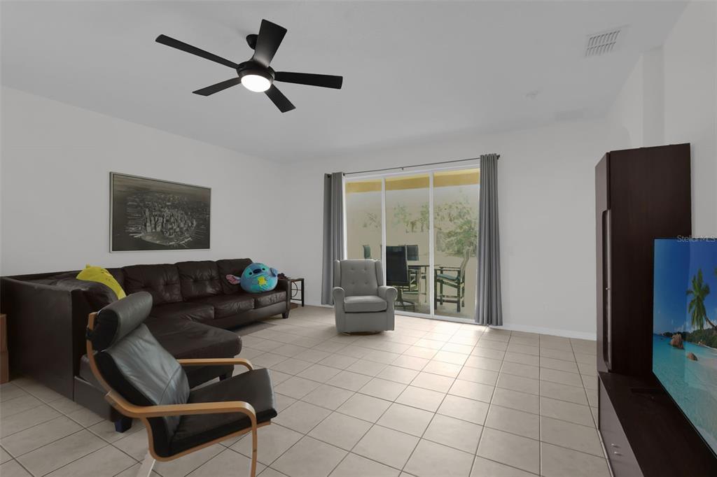 A living room features tile flooring, a dark sectional sofa, two armchairs, and sliding glass doors — 3940 HEATHCOTE DRIVE, ORLANDO, FL