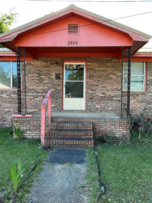 A brick house features a front porch with a red gable roof and metal supports — 2893 EVA MAE STREET, MARIANNA, FL