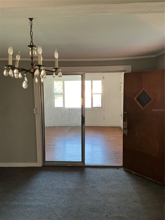A room with gray carpet and a chandelier looks through a sliding door into another room — 2893 EVA MAE STREET, MARIANNA, FL