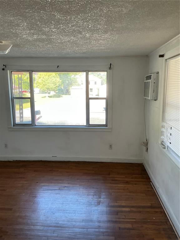 An empty room with hardwood floors, a large window, and a wall-mounted air conditioner — 2893 EVA MAE STREET, MARIANNA, FL
